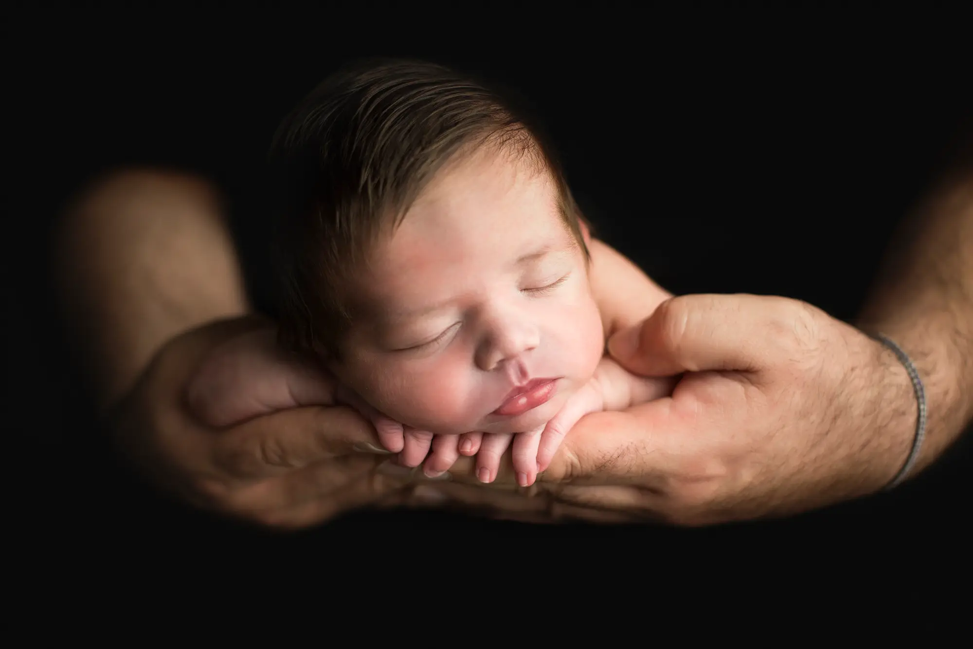 Neonato posato tra le mani durante una sessione fotografica